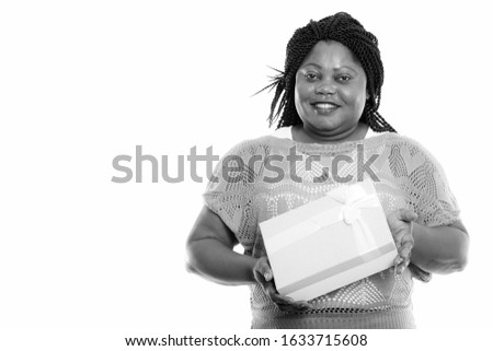 Studio shot of happy fat black African woman smiling while holding gift box