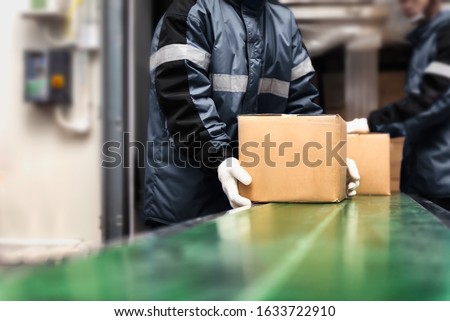Package boxes on conveyor belt in warehouse or loading area. Ready-made foods. Export-Import Logistics system concept. Royalty-Free Stock Photo #1633722910