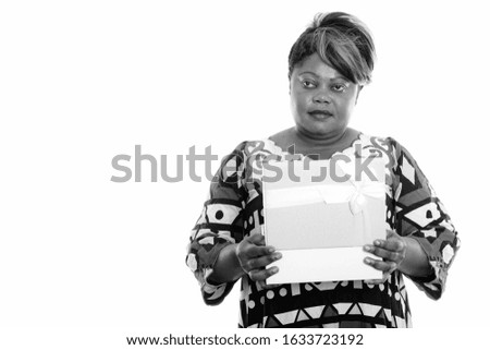 Studio shot of overweight African woman opening gift box while thinking