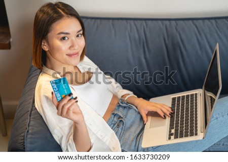 Charming cute girl using laptop computer and is going to pay online. Modern technologies concept