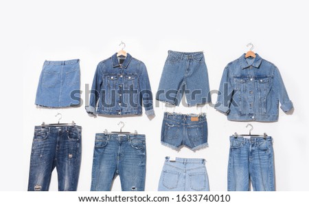 Two jeans jacket with three blue torn jeans on hanging and woman jeans skirt with jeans shorts a white background
