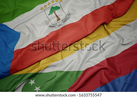 waving colorful flag of comoros and national flag of equatorial guinea. macro
