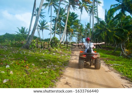 A group of people have fun on safari on quad bikes through the coconut beach near the shore