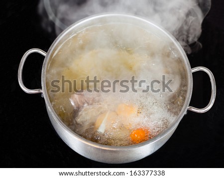 vapor over boiling of beef broth in pan on glass ceramic cooker