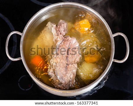 open pan with cooking beef broth with with seasoning vegetables