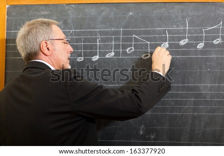 Music teacher writing notes on a blackboard