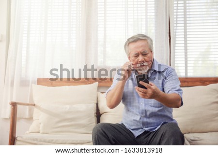 Older men move glasses down to look at the phone in the hand due to Hyperopia problems, which makes vision difficult.Health problems of the elderly. Royalty-Free Stock Photo #1633813918