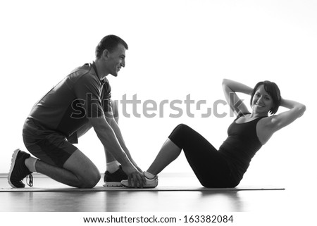 Woman does situps with coach in training gym abdominal silhouette studio isolated on white background 