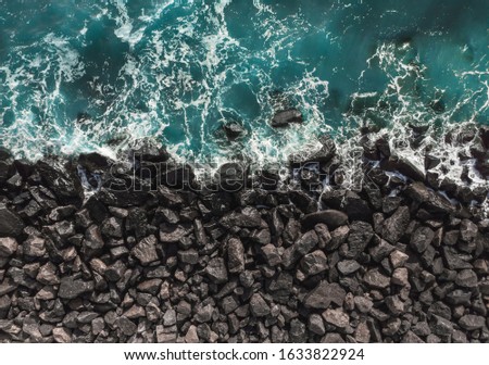 Top view of sea waves hitting rocks. Aerial view of sea water and beach coast with stones. Royalty-Free Stock Photo #1633822924