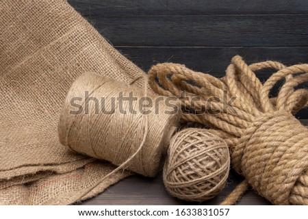 Jute rope and spools of burlap threads or jute twine in close-up on rustic wooden background Royalty-Free Stock Photo #1633831057