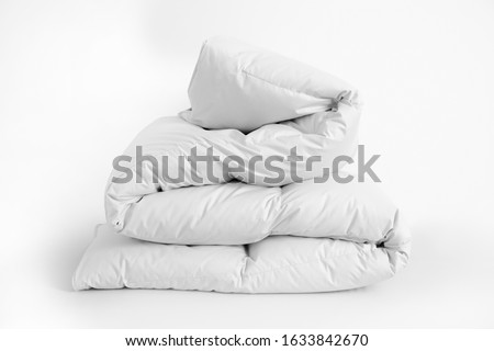 Folded soft white duvet, blanket or bedspread, against white background. Close up photo Royalty-Free Stock Photo #1633842670