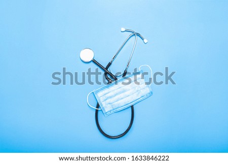 Medical stestoscope and protective mask on a blue background. Concept medicine, nurse, hospital, safety, epidemic. Banner. Flat lay, top view