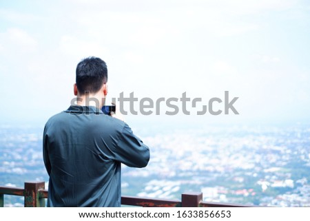 Portrait of Asian men tourist traveler take a photo on top view of mountain and blue sky with cityscape below. 