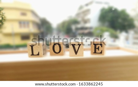 The image of square wooden blocks with four letters L, O, V, and E isolated on a wooden box, shot with blurred background for decorative design and Valentine's day.