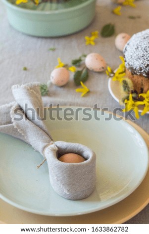 Wrapped Easter egg in a linen napkin in the shape of rabbit ears. Festive table setting in an ecological style.