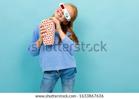 A girl with makeup and long brown hair, 3d glasses looks film or cartoon with popcorn