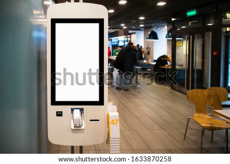Self-service desk with touch screen and payment terminal in fast food restaurant Royalty-Free Stock Photo #1633870258