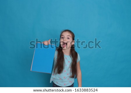 Cheerful loving girl of eight years old and a colored sheet of paper free space for recording on a azure background