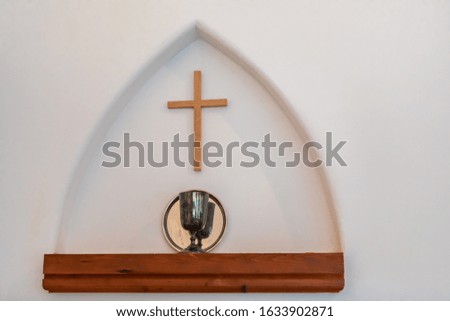 A wooden cross on church wall. Religious cross on interior wall of church. Religious christian symbol. Faith ,hope and love concept