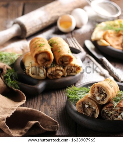 Concept of Russian cuisine. Pancakes with meat on a dark wooden background