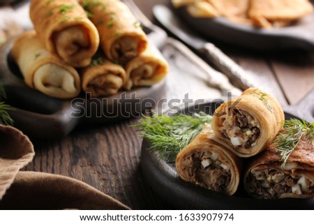 Concept of Russian cuisine. Pancakes with meat on a dark wooden background