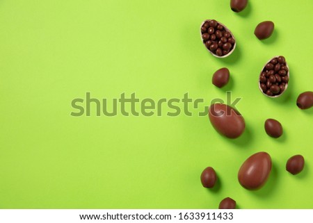 Egg hunt is coming. Easter traditions, chocolate eggs on green background, top view, copyspace for your ad or greetings. Concept of holidays, spring, celebrating, food and sweets, family time.
