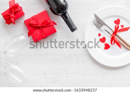 Romantic dinner on Valentines Day. Wine, plate, present box on white background top-down copy space