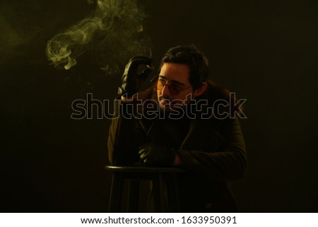 portrait of men in black jacket and black leather gloves and cigar in front isolated black background in the studio