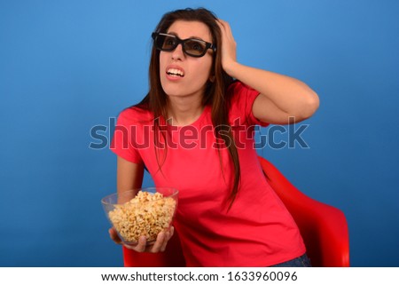 a man in a t-shirt watching a 3D movie with popcorn
