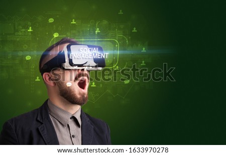 Businessman looking through Virtual Reality glasses with SOCIAL ENGAGEMENT inscription, social networking concept