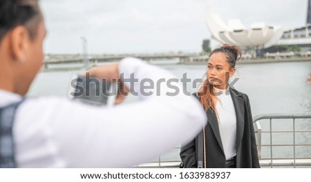 Asian man taking pictures of beautiful business woman visiting a new city.