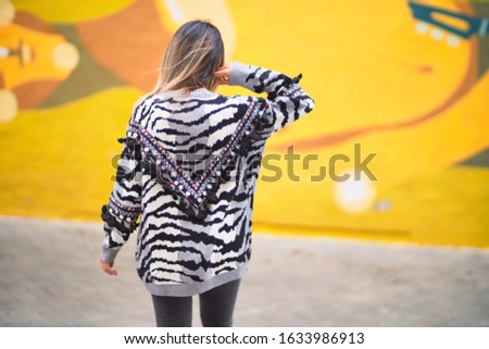 Young beautiful girl wearing sunglasses standing on backview at the town street,