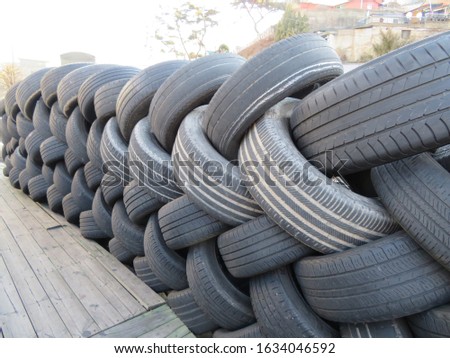 Used tires stacked in an interlocking pattern next to an auto garage parking lot in Seoul, Korea
