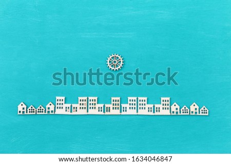 Wooden gear on city, decorate item for craft project, wood veneer in house and building shape with gear on blue texture background