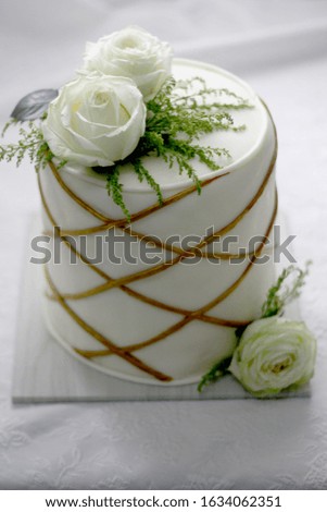 White color cake with gold stripe and white roses. White romantic background 
