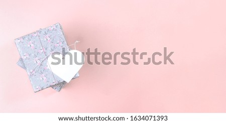 Valentine's day, Women's day or Mother's day  festive mockup banner. Gift boxes wrapped with grey paper with floral pattern and white paper heart  on pink background. Top view, copy space.