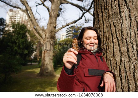 A woman holds a leaf of oak on a warm day in a spring park
