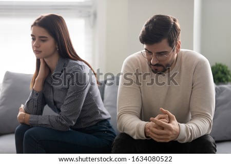 Young couple lost in sad thoughts sitting together on couch thinking feels troubled about problems in relationships, unwanted unexpected pregnancy and difficult decision, break up and divorce concept Royalty-Free Stock Photo #1634080522