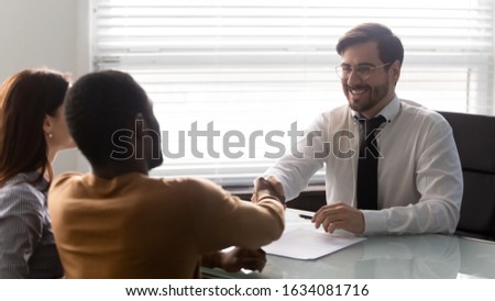 Financial advisor hands shake greets multiracial family at meeting in insurance trusted company office, bank manager congratulates real estate buyers first home-owners with housing improvement concept Royalty-Free Stock Photo #1634081716