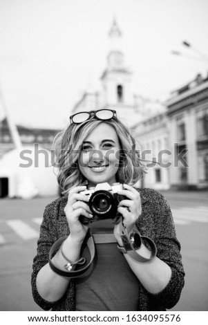 Portrait of a girl with a camera in the city. Black and white photo