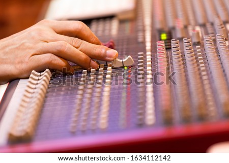 male sound engineer, dj hand working on audio mixing console. music production, post production, broadcasting concept