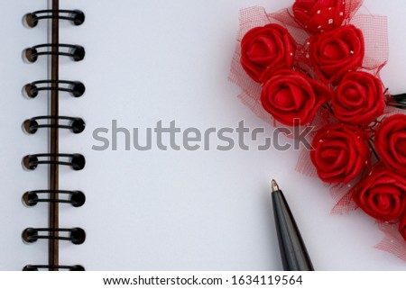 lots of red roses tied together lie on a notepad with a handle