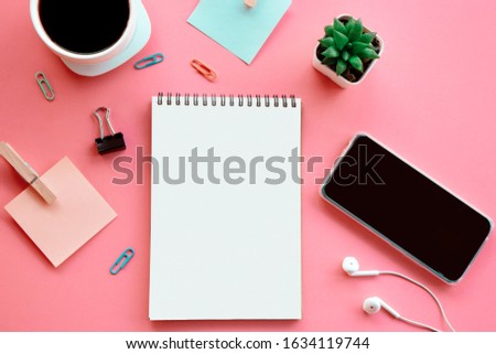 business flat lay on pink background with open note pad ,smart phone, paper note and coffee cup  
