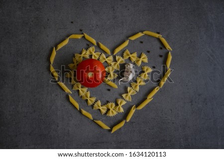 Still life with tomatoes, garlic and pasta. Close up food photo. Heart shape made of food. 