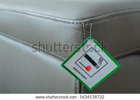 Fire resistant sign on new grey leather sofa. Royalty-Free Stock Photo #1634138722