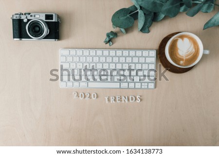 2020 trends for workspace with keyboard, mouse, camera and green leaf and coffee