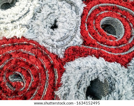 White and red warm and fluffy carpets rolled and stacked on each other as new carpets ready for sale in the store for home design decoration