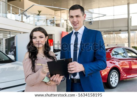 Woman signing contract with dealer in showroom