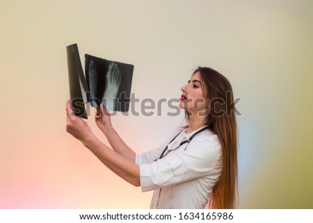 Attractive doctor comparing two x-rays of a patient with foot injury in hospital