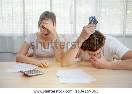 Young caucasian couple hand holding credit card and debt bill on table in home,men and women have overdue financial foreclosure problem sit in room with serious and unhappy payment. Royalty-Free Stock Photo #1634169865